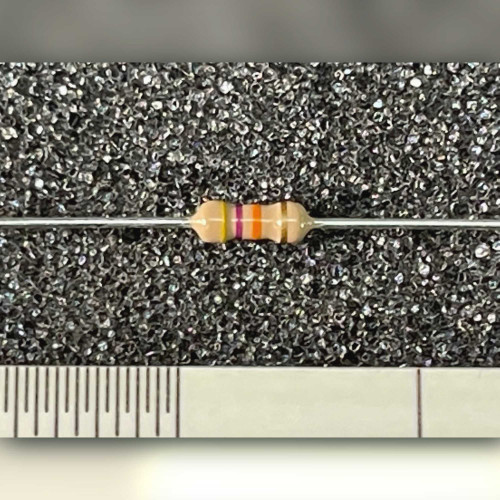 Cream cylindrical axial resistor with yellow violet orange gold bands on grey backdrop