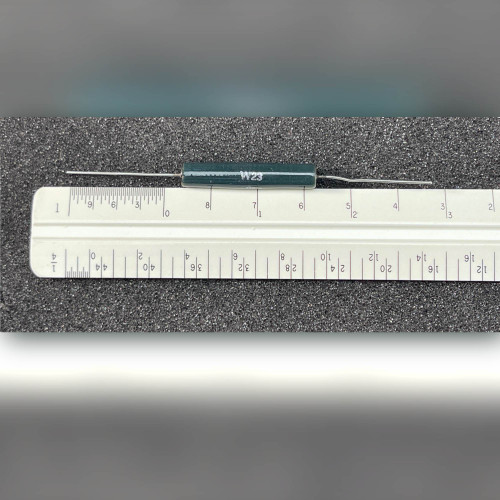 Dark green axial resistor marked W23 lying beside a ruler for scale
