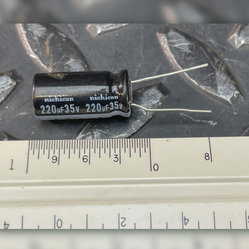 Nichicon 220uF 35V radial electrolytic capacitor beside PartsMine ruler, printed sleeve face up