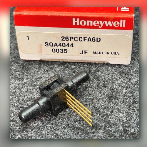 Honeywell 26PCCFA6D sensor with gold pins beside its open red and white Honeywell box on gray surface