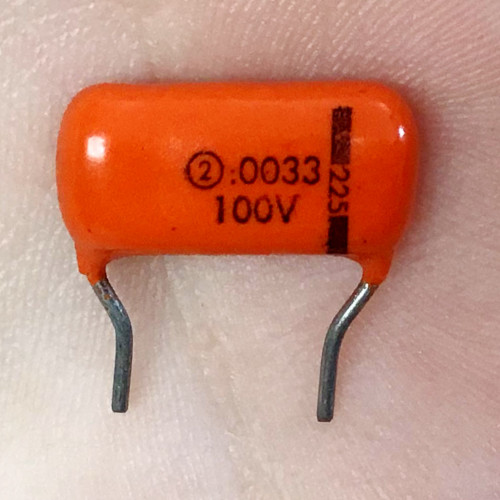 Sprague 225 Orange Drop capacitor on white paper, body printed .0033 and 100V