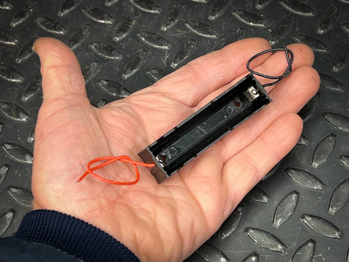 Black plastic single-cell holder with red and black wire leads, unoccupied cell bay, no visible wear or damage.