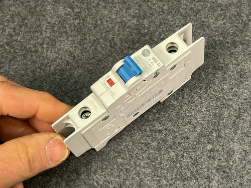 Hand holding Allen Bradley 1489-M1C040 circuit breaker at an angle, blue toggle raised.