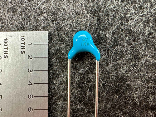 Capacitor body clean, leads long and straight, showing no corrosion. Markings "47 1KV" clearly visible.