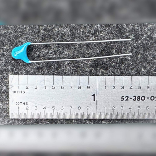 Blue radial ceramic capacitor with long leads shown next to a ruler for scale.