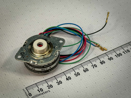 Haydon 06-0024-00 stepper linear actuator at an angle beside millimeter ruler, color-coded leads coiled