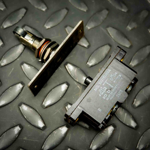 Cutler-Hammer 10316H89A Snap Action Switch with Roller Plunger assembly from PartsMine.com, shown disassembled with the plunger and switch body placed on a textured metal surface.