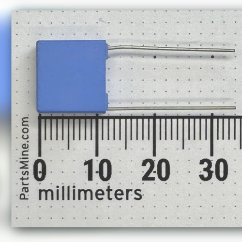 Flat mid-blue rectangular capacitor beside a millimetre ruler, two straight radial leads from one edge