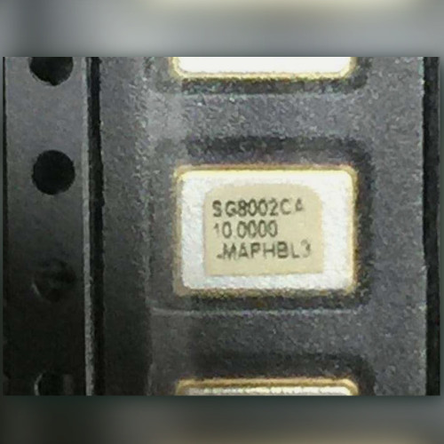Carrier-taped SMD oscillator labeled SG8002CA, 10.0000, MAPHBL3, neighboring parts partly in frame