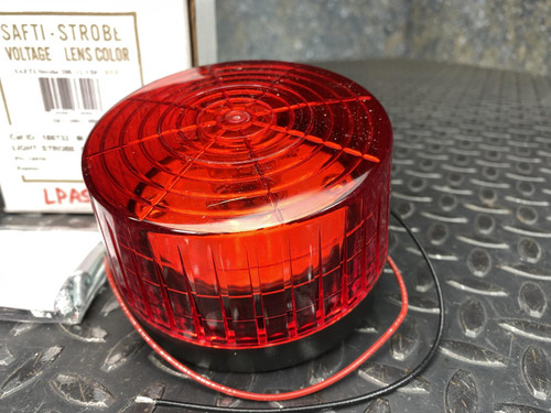 Red ribbed polycarbonate lens, black ABS base, two lead wires visible. Unit appears clean with no visible wear or damage.