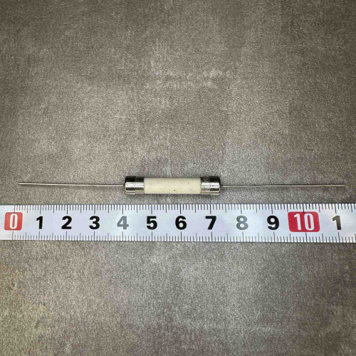 Five Littelfuse ceramic cartridge fuses with long axial wire leads on gray background