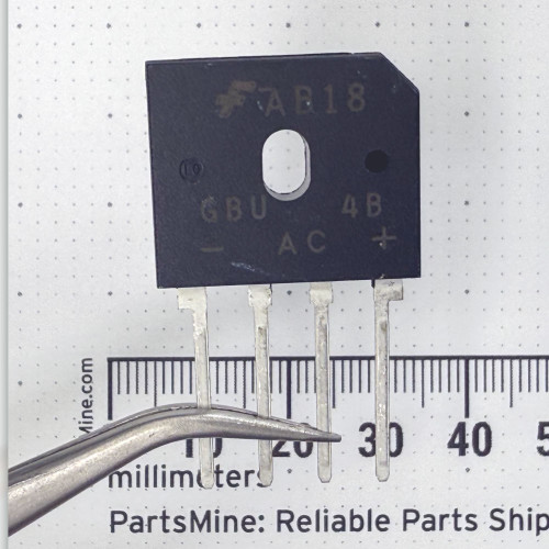 Black molded GBU package, four flat leads with visible tarnish. Marked: Fairchild logo, AB18, GBU4B, pin labels -, AC, AC, +.