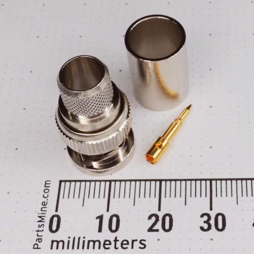 Three-piece connector set: nickel-plated body with knurled coupling ring, separate crimp ferrule, and gold-plated center pin. Body spans roughly 20mm per ruler.