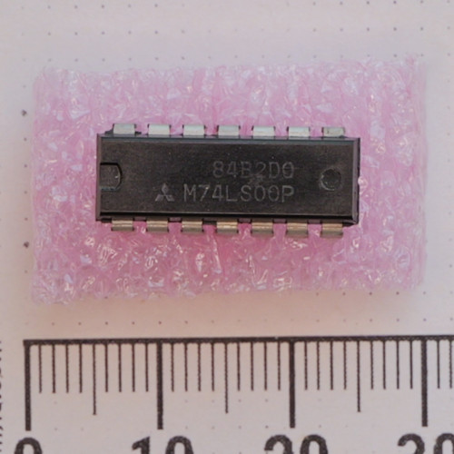 Top view of Mitsubishi M74LS00P 14-pin DIP IC on pink foam next to a ruler.