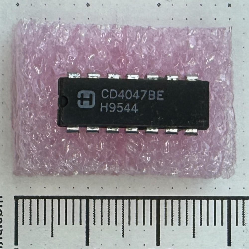 Top view of Harris Semiconductor CD4047BE 14-pin DIP integrated circuit on pink foam.