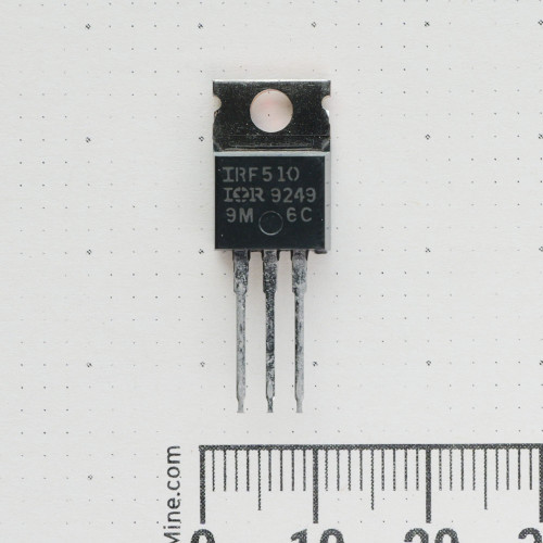Front view of IOR IRF510 power transistor in a TO-220 package against a scale ruler.