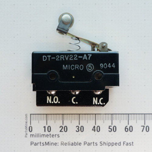 Front side view of Micro Switch DT-2RV22-A7 with roller actuator next to a millimeter scale.