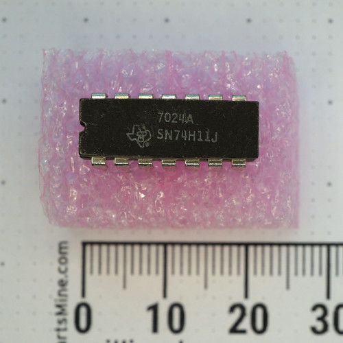 Top view of Texas Instruments SN74H11J integrated circuit on pink foam with metric ruler.
