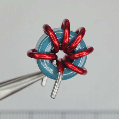 Front view of Digi-Key PA0689 toroidal inductor held with tweezers.