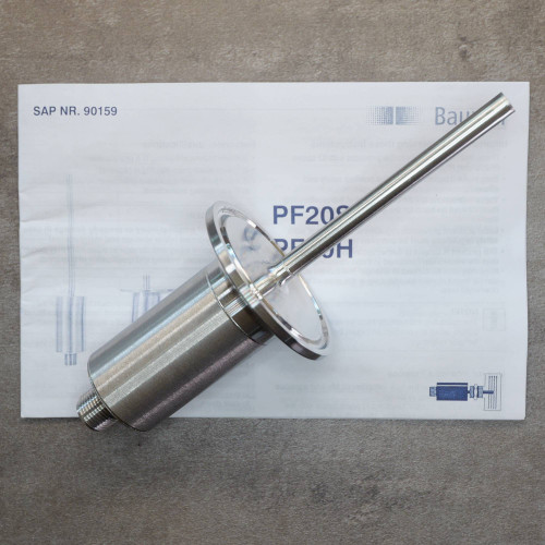 Baumer PF20H flow sensor resting on included instruction manual.