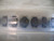 Seven SMD inductors in tape, each with red/red/yellow dot markings on black toroid bodies. No visible damage.