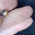 Small metal-can transistor with dark body, gold-toned flange, and three long gold leads fanned across a palm.