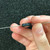 Thru-hole resistor held between a person's fingers, featuring a black cylindrical body and silver leads, with the visible markings "TEPRO TS 1W 75 0.05%" printed in white text.
