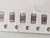 Five brown ceramic chip capacitors in paper tape with sprocket holes along bottom edge