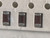 Macro of three brown ceramic chip capacitors in white tape pockets, sprocket holes above