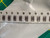 Strip of nine taped chip capacitors on a white bag, green mat at the edges