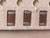 Macro of three brown chip capacitors seated in white carrier tape, holes above