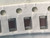 Tilted tape with three dark maroon chip capacitors and large sprocket holes above
