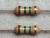 Two carbon film resistors, color bands Brown, Green, Green, Gold. Leads appear clean, no visible oxidation or damage.