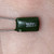 Green dipped 2A223J polyester film capacitor held in palm, white marking legible, leads bright