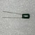 2A223J film capacitor on white textured background, full view, bright radial leads, upper lead slightly kinked