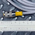 Knurled nickel-plated connector with yellow strain relief boot; gray cable jacket printed with partial text including POLYURE visible. Connector spans roughly 1.5 inches by ruler.