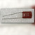 Dark red-brown dipped capacitor on a palm, marking 563K over 100N in grey