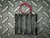 Black plastic 4-cell AA battery holder with coil spring contacts, red and black wire leads, and molded polarity symbols on each bay.
