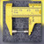 51NM glass fuse held in yellow caliper jaws, body reading roughly 20 mm long
