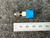 Top-down view of the Swagelok SS-100-1-2 Male Connector, 1/16" Tube OD x 1/8" NPT from PartsMine.com attached to a blue plastic cap, placed next to a metric ruler on a gray surface.