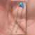 Blue 56pF 1KV ceramic capacitor with long radial leads resting in a hand.