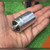 Hand holding CG42U100A1 aluminum can capacitor, terminal end and clear Mylart sleeve visible