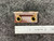 Federal Pacific F1.42 Thermal Overload Heater Element, a rectangular industrial electrical component featuring a reddishbrown insulating base with two prominent brasscolored eyelet terminals. A coiled metallic resistive element is mounted on the upper section. The heater element is shown approximately 2 inches long, indicated by a ruler, against a dark gray textured background, highlighting its design for circuit protection and electrical control panel applications as a replacement part.