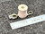 Angled view of tan spool body, stamped terminal tab and brass eyelets near ruler.