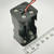 Black plastic 2x2 stacked AA holder with red and black lead wires; three star-contact terminals and two coil springs visible; ruler confirms approximately 50mm height.