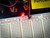 A23040 5mm red LED glowing on breadboard, wider view with yellow PartsMine label