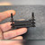 Clamp held in hand showing three bars, foam layers and two black tipped posts