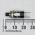Side view of C&K 8551MZQE2 pushbutton switch next to a metric ruler showing hardware and approx 26 mm overall length.