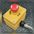 Allen-Bradley yellow E-Stop station with red 40mm mushroom button, angled top view on steel plate