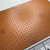 Bare phenolic perfboard surface, no copper pads, uniform hole grid, faint red stamped markings on edges and lower face. Minor surface patina visible.